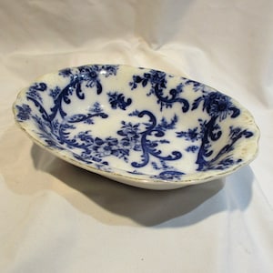 May include: A white oval serving bowl with a blue and white floral pattern. The bowl has a scalloped edge and is made of ceramic.