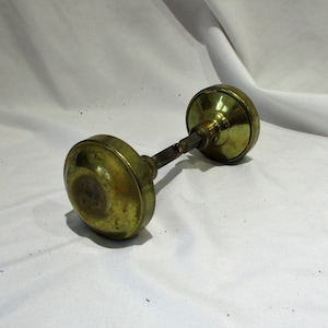 May include: A pair of antique brass door knobs with a tarnished finish. The knobs are round and have a simple design.