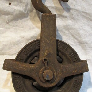 Pu&ograve; includere: Una carrucola in ghisa vintage con un gancio, etichettata "The Val. Ho. Differential Pulley Harlem, N.Y."