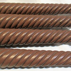 May include: Four brown wooden table legs with a rope-like design. The legs are all the same size and shape.