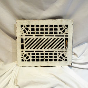 May include: White cast iron floor register with a geometric design. The register has a black and white pattern with a decorative border.