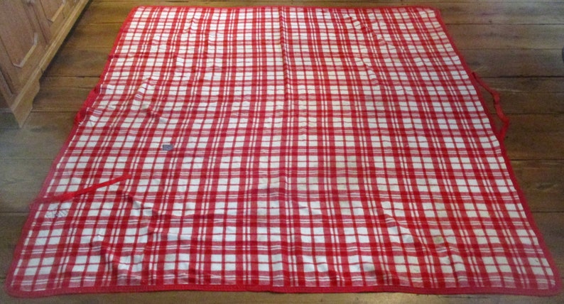 May include: Red and white checkered picnic blanket with red trim and handles.