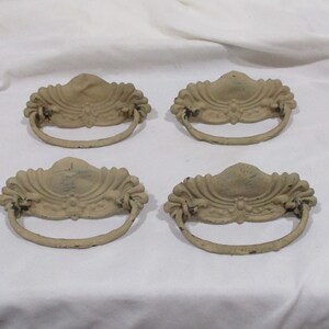 May include: Set of four antique-style cabinet pulls with a decorative floral design. The pulls are made of metal and have a distressed white finish.