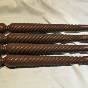 May include: Five dark brown wooden table legs with a twisted design and a rounded top.