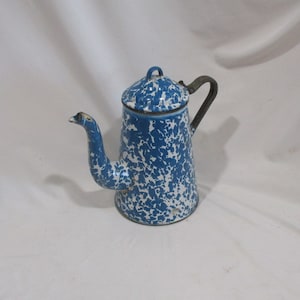 May include: Vintage blue and white speckled enamelware coffee pot. The coffee pot has a lid, a spout, and a handle. The blue and white pattern is reminiscent of a classic farmhouse style. The pot is likely made of metal and is a classic kitchenware item.