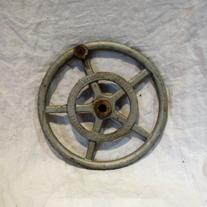 May include: A silver metal hand wheel with a six-spoke design. The wheel is labeled "American  Bridge Co. New York, U.S.A."