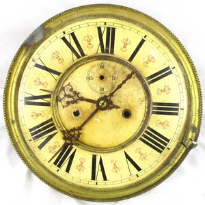 Peut inclure: Cadran d'horloge ancien avec un fond cr&egrave;me et des chiffres romains noirs. Le cadran a un cadre en m&eacute;tal dor&eacute; et des accents floraux rouges d&eacute;coratifs. Les aiguilles sont marron fonc&eacute;, et un petit cadran indique les secondes.
