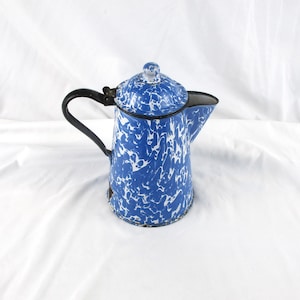 May include: Blue and white enamelware coffee pot with a black handle and spout. The pot has a speckled pattern and a lid with a small knob. A classic kitchenware item.