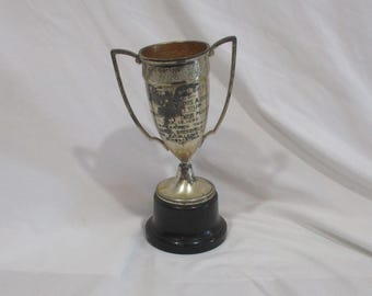 May include: Silver trophy cup with black base. The cup has engraved text that reads "The Doris A. Cook Cup 1919-1923 Awarded To The Winner Of The Annual Bowling Tournament".
