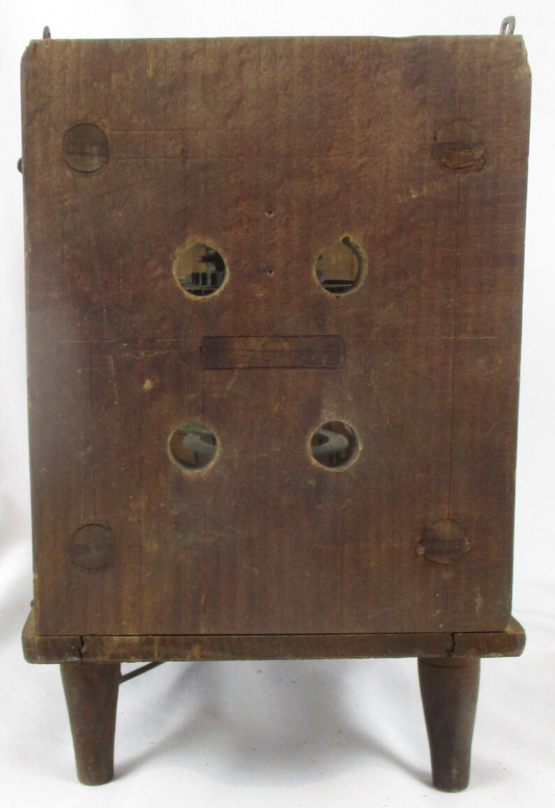 May include: A vintage wooden radio cabinet with a dark brown finish. The back of the cabinet features four circular openings, two rectangular openings, and four small wooden feet. The cabinet has a rectangular shape.