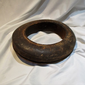 May include: A dark brown wooden hat form, shaped like a ring, with a smooth, worn surface.