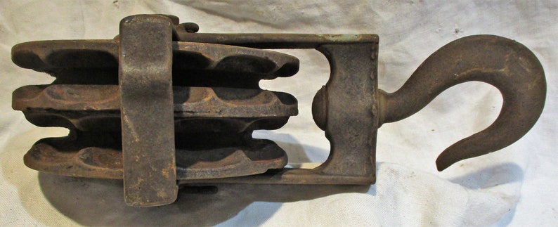 Pu&ograve; includere: Una carrucola vintage in ghisa con un gancio. La carrucola ha quattro scanalature ed &egrave; realizzata in metallo grigio scuro. Il gancio &egrave; anch'esso realizzato in metallo grigio scuro ed &egrave; piegato ad un angolo di 90 gradi.