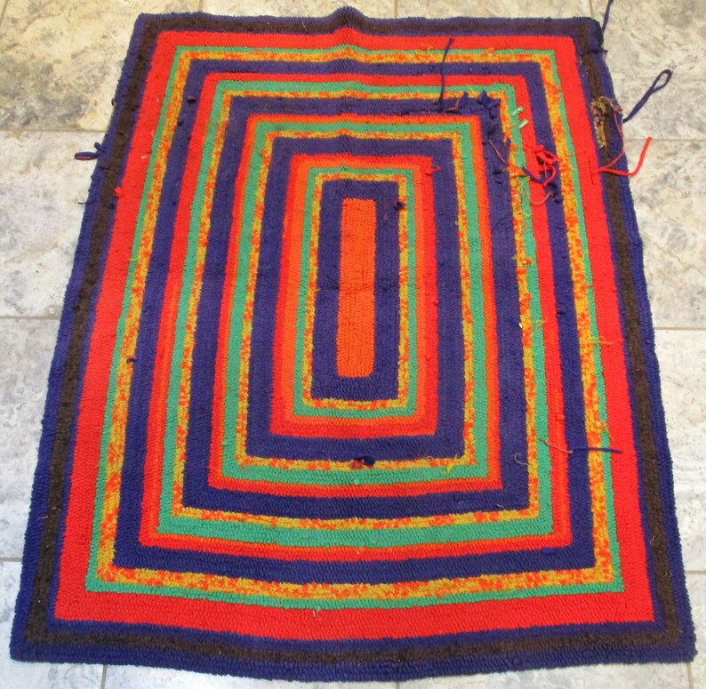 May include: A colorful braided rug with a multi-layered design. The rug features stripes of red, orange, yellow, green, and blue.