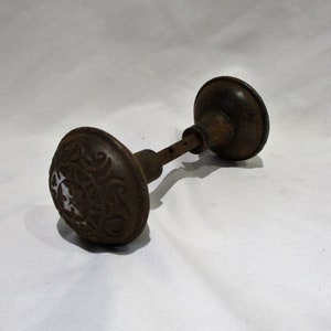 May include: A vintage, rusty, cast iron door knob with an ornate design. The knob is in a worn condition, showing signs of age and use.