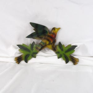 May include: A colorful bird figurine perched on a branch with green leaves. The bird has yellow, red, and green feathers. The branch and leaves are brown and green. This decorative piece is ideal for adding a touch of nature to any space.