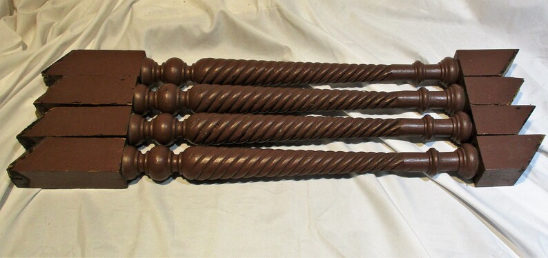 May include: Four dark brown wooden table legs with a twisted design and a rounded top.