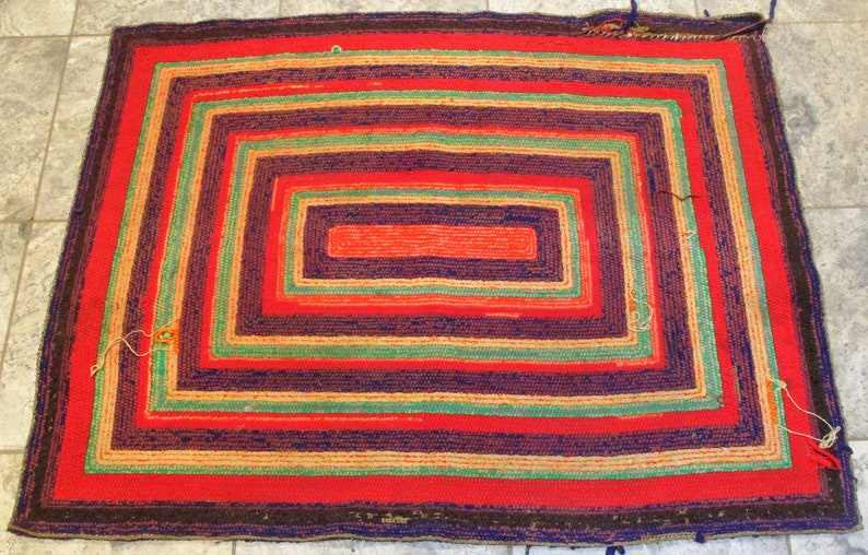 May include: A hand-woven rug with a multi-colored concentric square pattern. The rug is made of wool and has a rustic, vintage look.