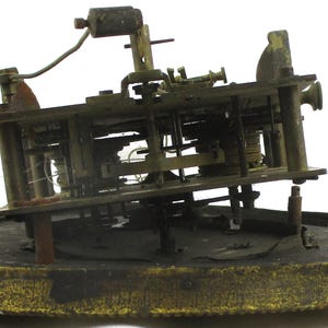 Peut inclure: Un mouvement d'horloge ancien, pr&eacute;sentant des engrenages et des m&eacute;canismes complexes. Les composants de couleur laiton sont mont&eacute;s sur une base circulaire. Le fonctionnement interne de l'horloge est visible, avec un accent sur la construction et la conception d&eacute;taill&eacute;es.