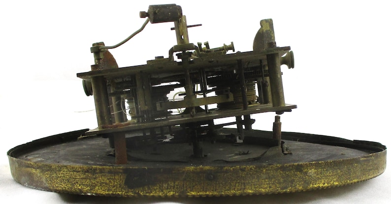Peut inclure: Un mouvement d'horloge ancien, pr&eacute;sentant des engrenages et des m&eacute;canismes complexes. Les composants de couleur laiton sont mont&eacute;s sur une base circulaire. Le fonctionnement interne de l'horloge est visible, avec un accent sur la construction et la conception d&eacute;taill&eacute;es.