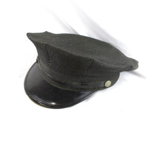 May include: A dark gray, peaked cap with a shiny black visor. The cap has a rounded crown and a small, circular button on the side. The visor is curved and attached to the cap with a thin, black band.