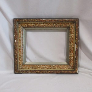 May include: A vintage picture frame with a gold and brown finish. The frame has a decorative border with a textured pattern.