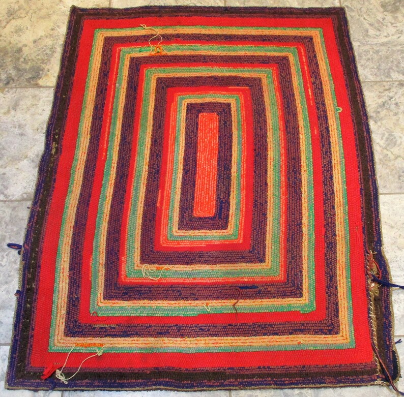 May include: A hand-woven rug with a multi-colored striped pattern. The rug has a rectangular shape and is made of natural fibers. The colors of the stripes are red, green, blue, and brown.
