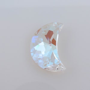 May include: A clear iridescent crescent moon shaped crystal embellishment.