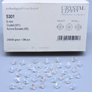 May include: A box of 288 clear crystal beads with an iridescent finish. The box is labelled "Crystal Lizer Swarovski Elements" and includes the product number 5301, size 8 mm, and the description "Crystal (001) Aurore Boreale (AB)".