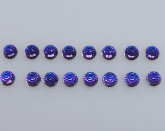 Puede incluir: Dieciséis cuentas redondas facetadas en tonos morados y azules están dispuestas en cuatro filas. Las cuentas tienen un aspecto texturizado, similar a una gema, que refleja la luz. Ideales para la creación de joyas o proyectos de artesanía.