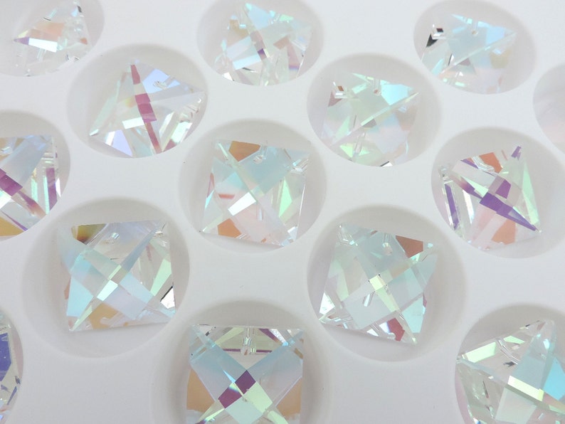Puede incluir: Cristales cuadrados iridiscentes con m&uacute;ltiples facetas, expuestos en una bandeja blanca. Los cristales reflejan un arco&iacute;ris de colores, incluyendo azul, verde y morado. Los cristales est&aacute;n dispuestos en un patr&oacute;n de cuadr&iacute;cula.