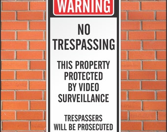 May include: A rectangular white sign with black text against a red brick wall. The sign reads "WARNING" at the top, followed by "NO TRESPASSING" and "THIS PROPERTY PROTECTED BY VIDEO SURVEILLANCE." The bottom text states "TRESPASSERS WILL BE PROSECUTED."