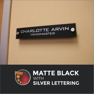 May include: Matte black nameplate with silver lettering, mounted on a beige wall. The nameplate reads "CHARLOTTE ARVIN" above "HEADMASTER". The bottom of the image shows the text "MATTE BLACK WITH SILVER LETTERING".