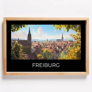 May include: A framed print of a painting depicting a cityscape with a church steeple in the center. The city is surrounded by trees and the sky is blue with white clouds. The text "FREIBURG" is printed below the image.