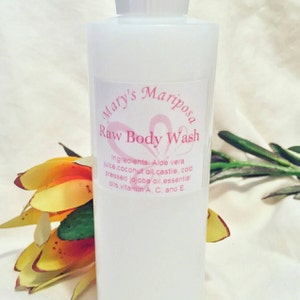 May include: A white bottle of "Mary's Mariposa Raw Body Wash" with a pink label. The label lists ingredients like aloe vera juice, coconut oil, and essential oils. A colorful flower and green leaves are in the background.