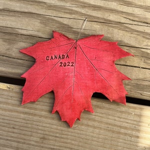 K&ouml;nnte beinhalten: Ein rotes Ahornblatt mit dem Aufdruck "CANADA 2022".