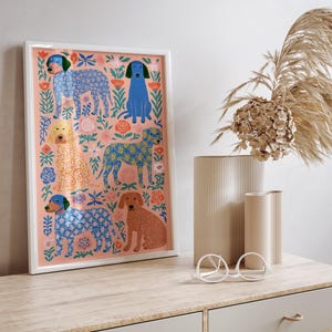 Puede incluir: Una l&aacute;mina de arte mural rectangular enmarcada con un fondo color melocot&oacute;n y un patr&oacute;n repetitivo de cinco perros en varios colores y motivos florales. Los perros est&aacute;n representados en azul, amarillo y marr&oacute;n, rodeados de flores estilizadas.