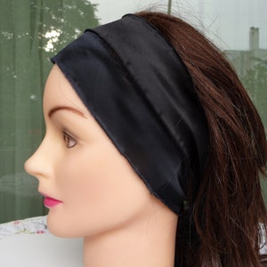 May include: A black satin headband for hair. The headband is wide and has a smooth, silky texture.