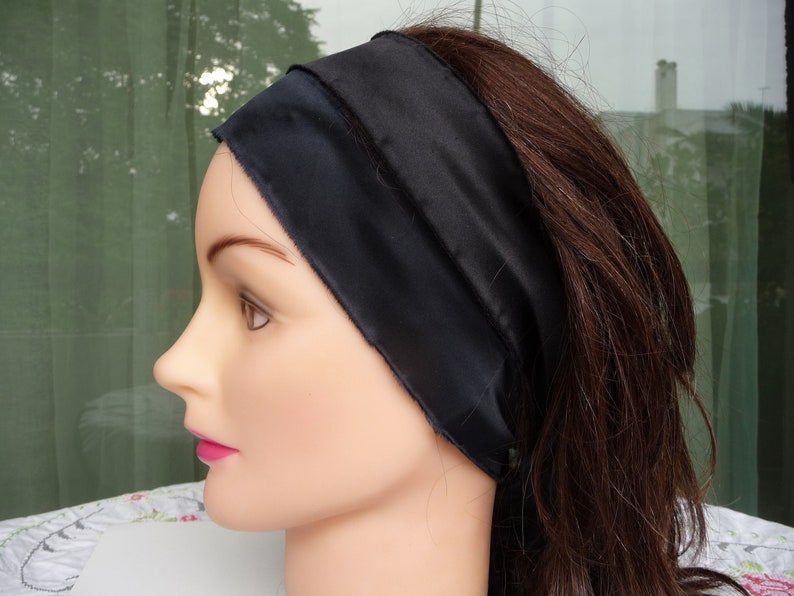 May include: A black satin headband for hair. The headband is wide and has a smooth, silky texture.