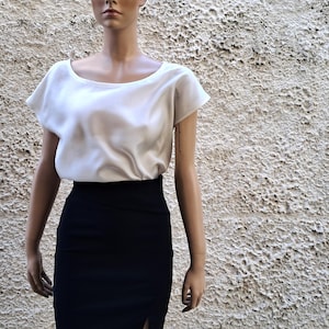K&ouml;nnte beinhalten: Eine wei&szlig;e Bluse mit kurzen &Auml;rmeln, Rundhalsausschnitt und schwarzem Bleistiftrock.