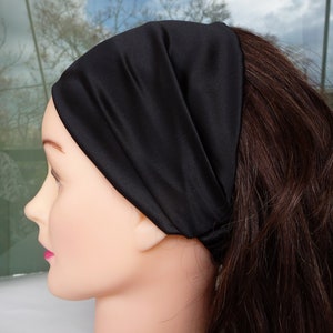 May include: A black satin headband for hair. The headband is worn on a mannequin with long brown hair.