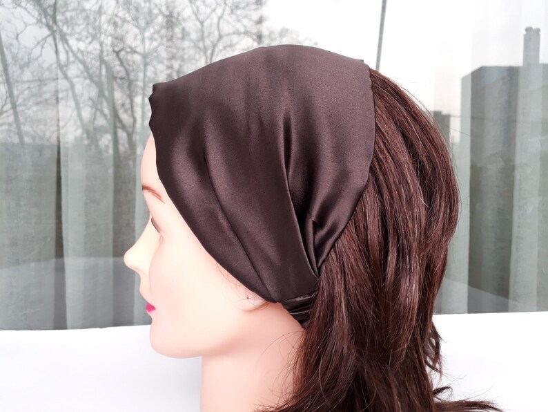 May include: A brown satin headband for hair. The headband is folded and tied at the back of the head.