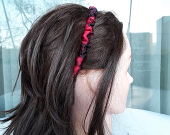 Könnte beinhalten: Ein rotes und schwarzes gemustertes Haarband.