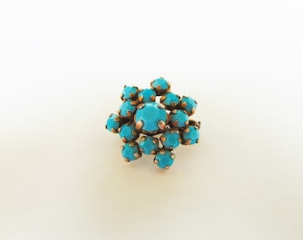 May include: A gold ring with a cluster of turquoise blue stones set in a starburst pattern.