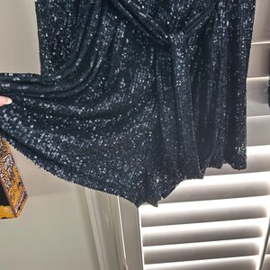 May include: Black sequined shorts with a knotted waistband. The shorts are made of a soft, stretchy fabric and have a comfortable fit.