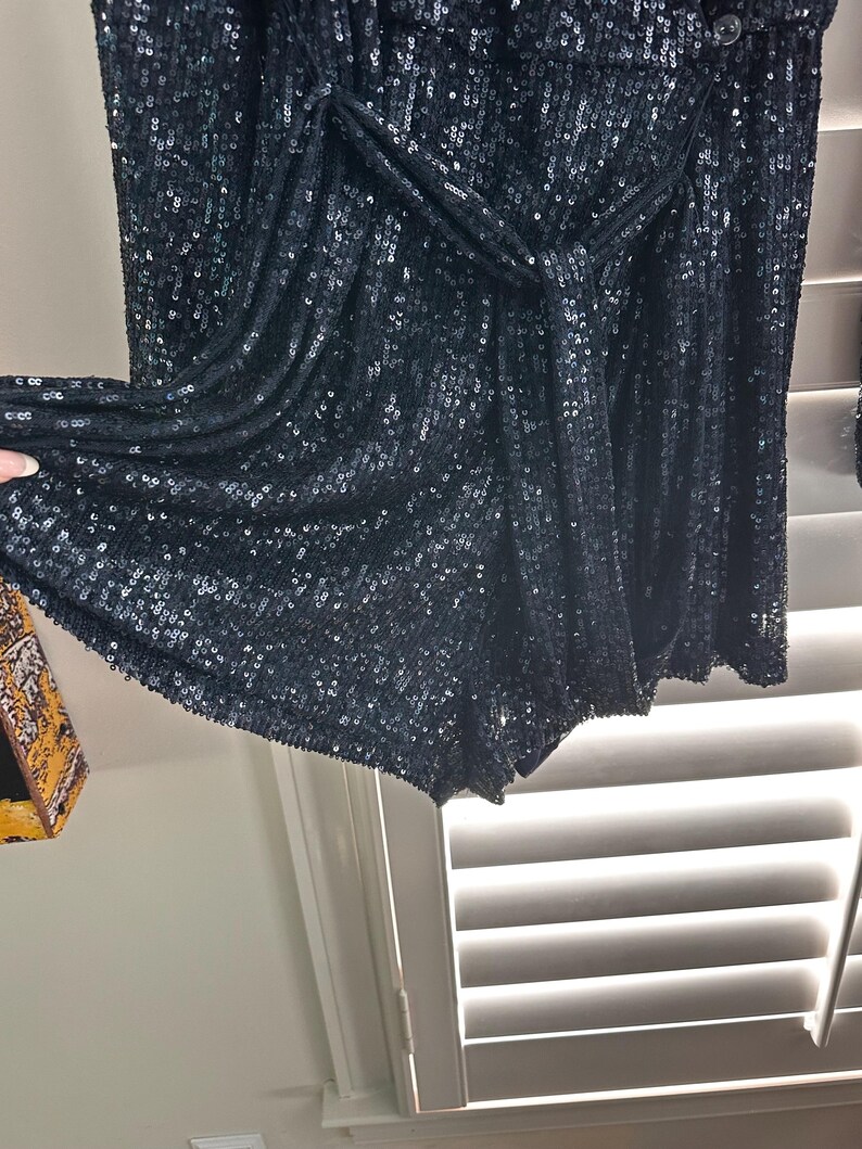 May include: Black sequined shorts with a knotted waistband. The shorts are made of a soft, stretchy fabric and have a comfortable fit.