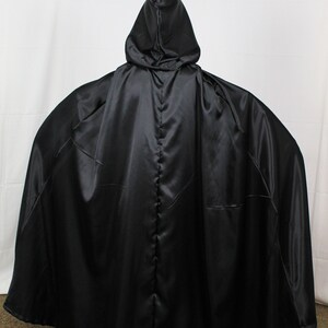 May include: A black satin hooded cape with a long flowing design.