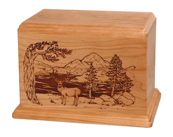 May include: A wooden cremation urn with a laser-engraved design of a deer standing in a forest scene with mountains and a lake in the background.