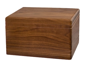 May include: A rectangular wooden box with a dark brown walnut finish. The box has a smooth, polished surface and a slightly rounded top.