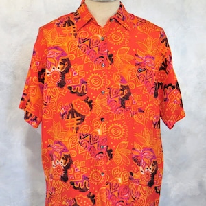May include: A short-sleeved button-down shirt with a bright orange background and a colorful abstract pattern. The pattern features pink, orange, yellow, and black geometric shapes and designs.
