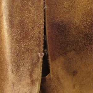 May include: Close-up of a brown suede jacket with a seam down the back.